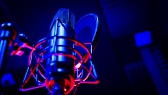 Cozy radio studio with vintage microphone and colorful sound equipment bathed in medium blue light.