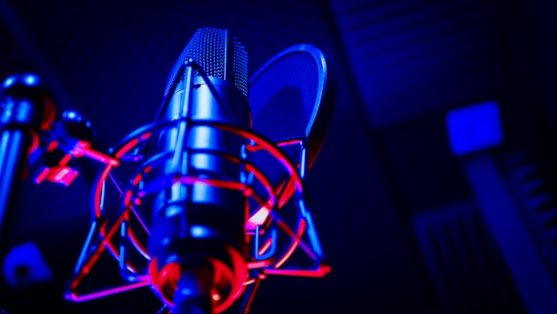 Close-up of a microphone with soft colorful lights resembling a cozy recording studio atmosphere.