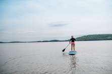 a woman standing on a paddle board in the water