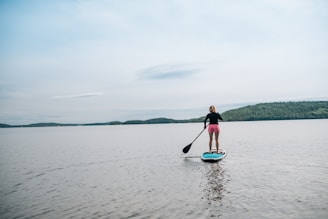 a woman standing on a paddle board in the water