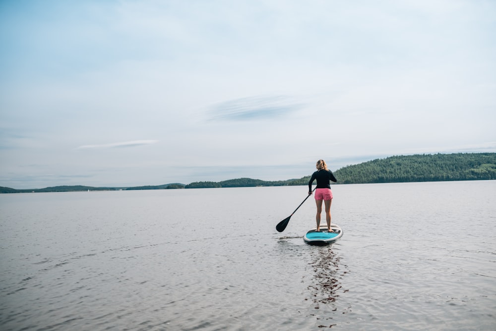 a woman standing on a paddle board in the water