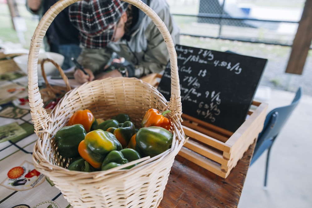 a basket of peppers sitting on top of a wooden table