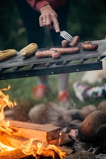 a person grilling hot dogs over a fire