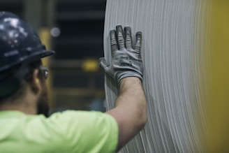 a man in a hard hat and safety gear working on a piece of metal