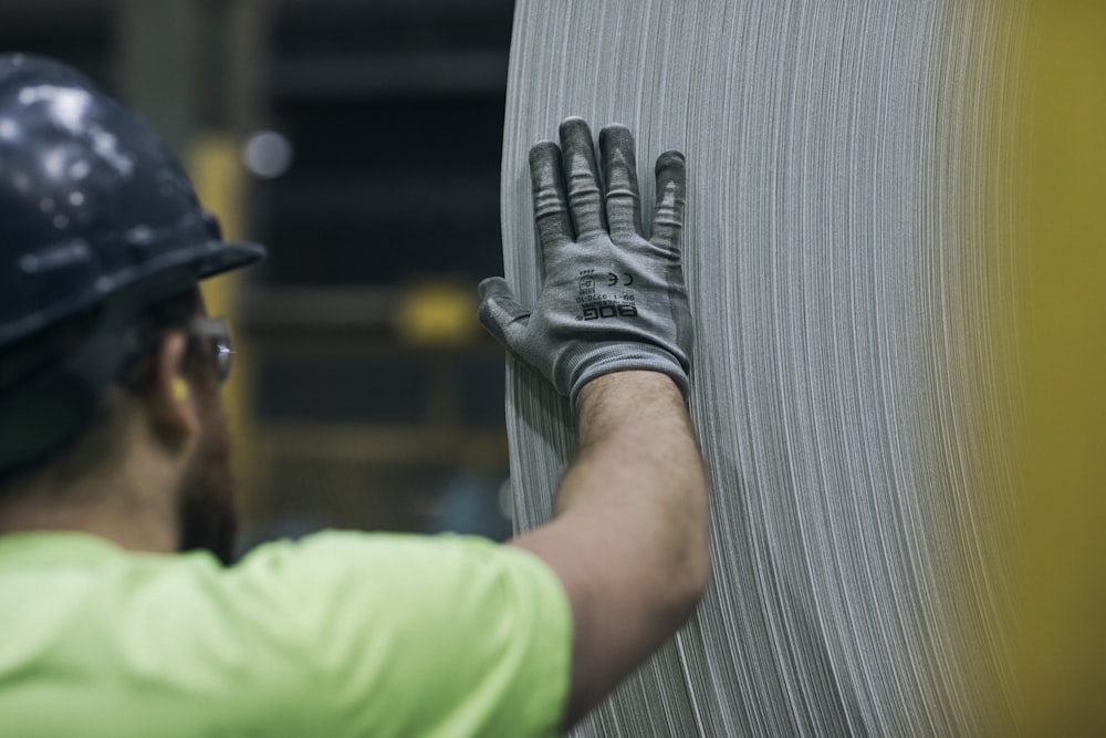 a man in a hard hat and safety gear working on a piece of metal