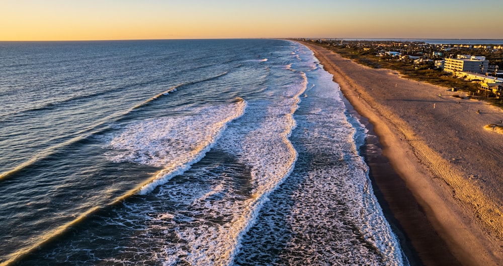 an aerial view of a beach and ocean at sunset