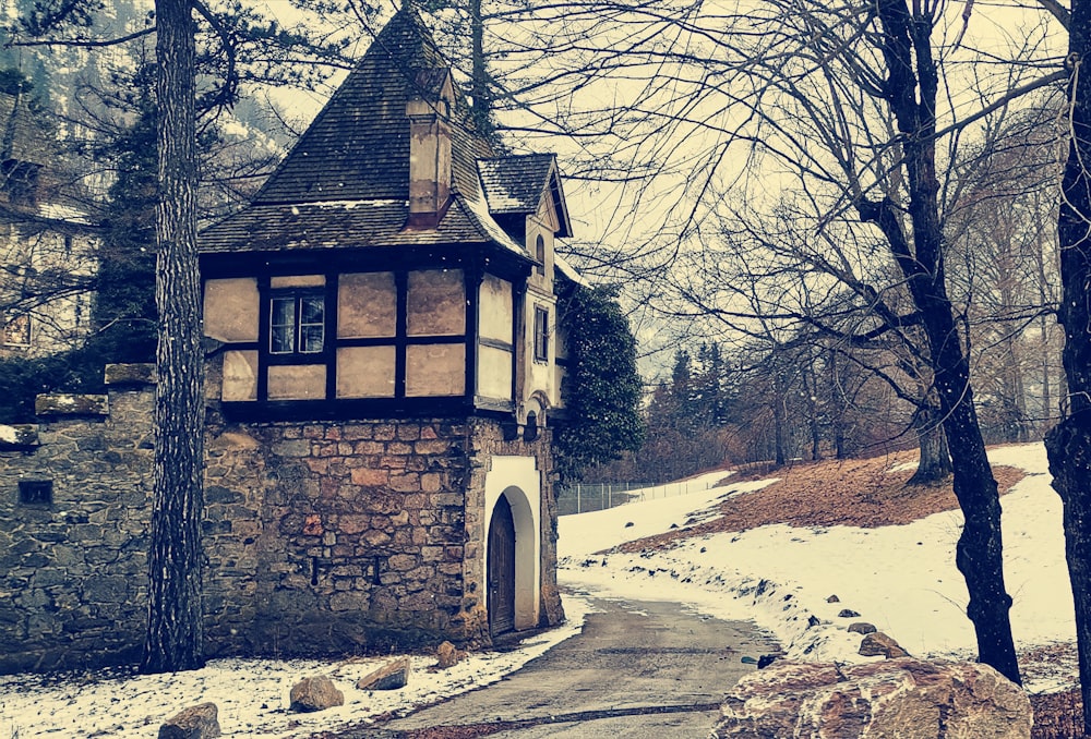 a stone building with a tower in the middle of a snowy forest