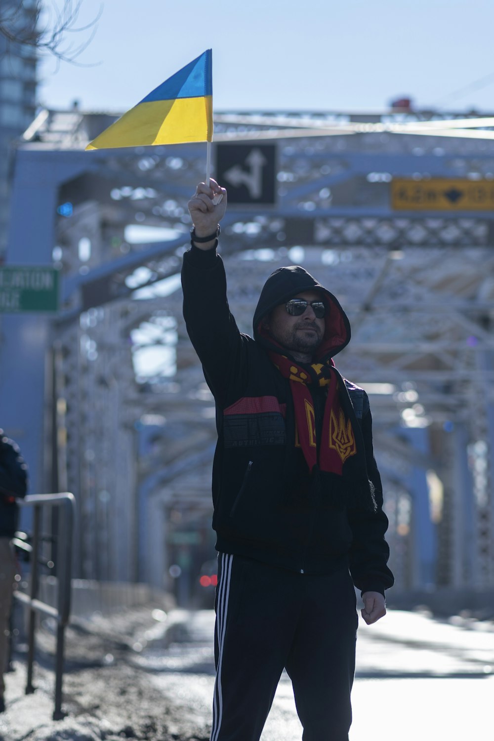 a man in a black jacket holding a yellow and blue flag