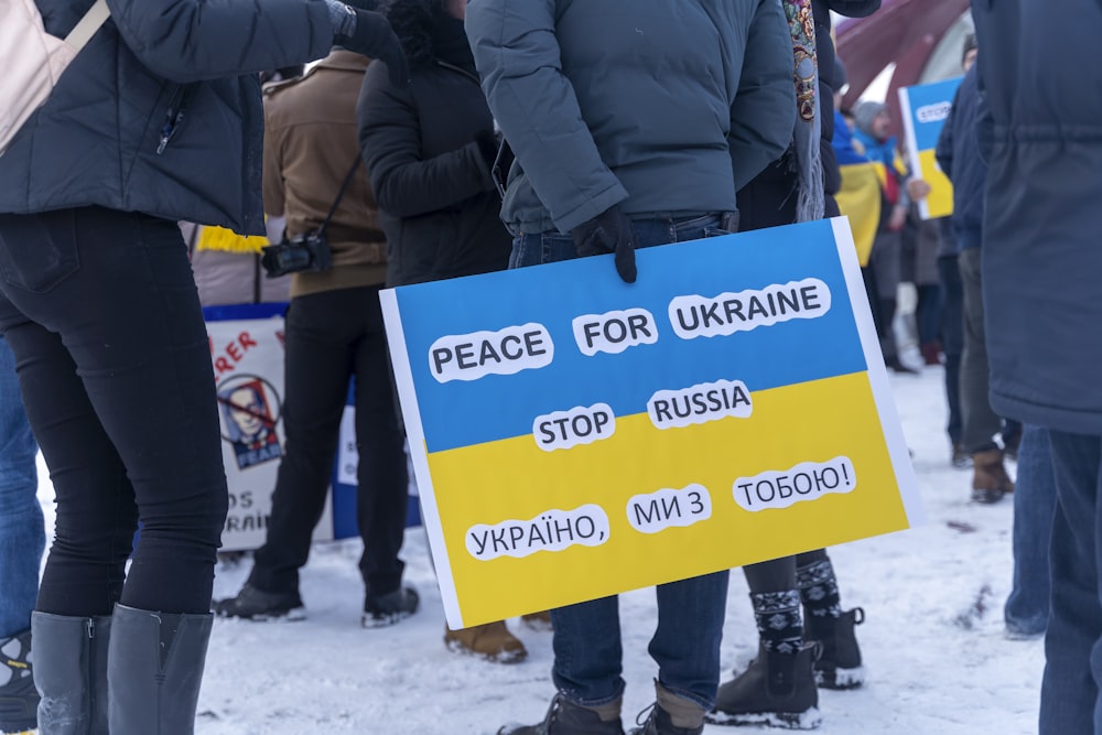 a group of people standing in the snow holding signs