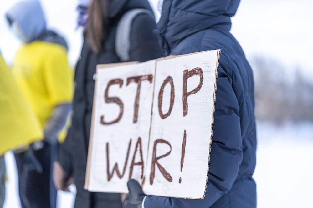 Una persona sosteniendo un cartel que dice Alto a la Guerra