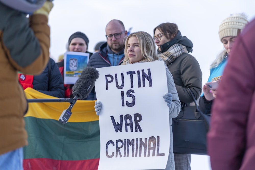 a woman holding a sign in front of a crowd