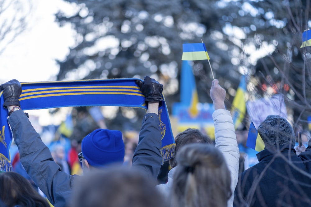a group of people holding up blue and yellow flags