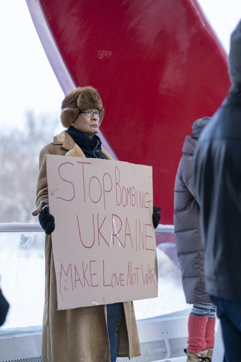 Una mujer sosteniendo un cartel que dice Stop Bombardeing Ukraine Make Love Not War