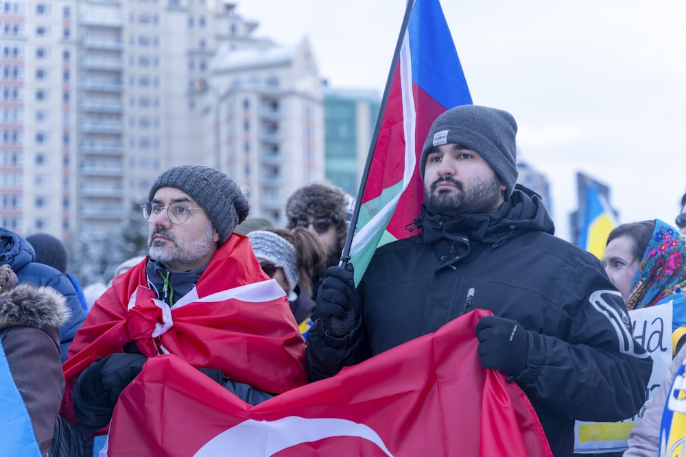 a group of people standing around each other holding flags