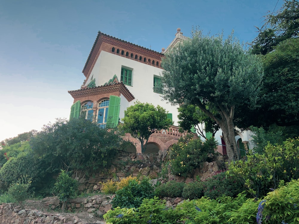 a white house with green shutters on a hill