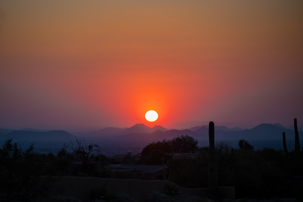 the sun is setting over a mountain range