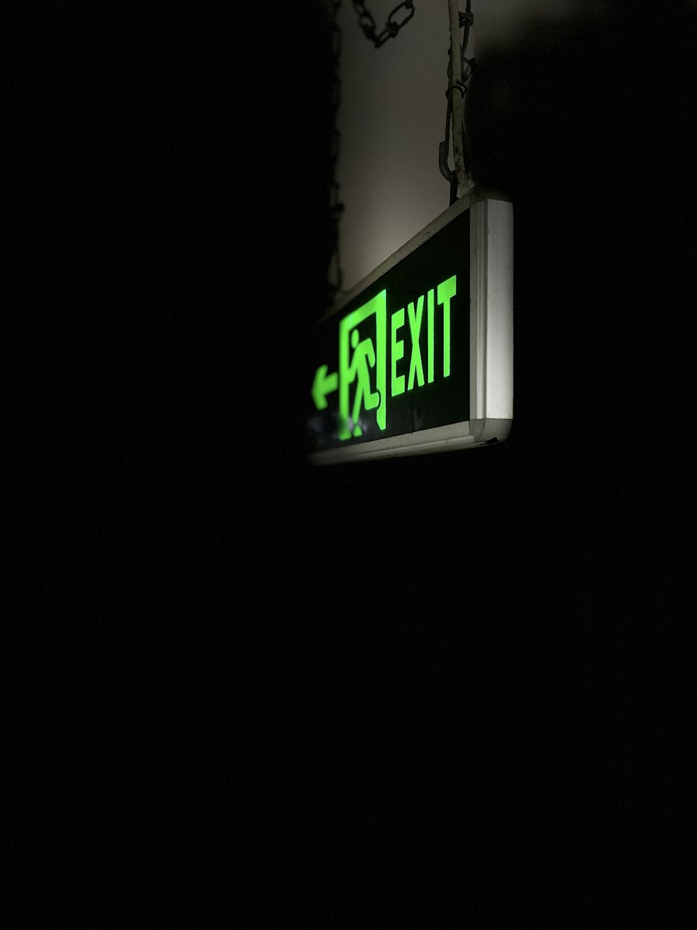 a green exit sign hanging from the side of a building