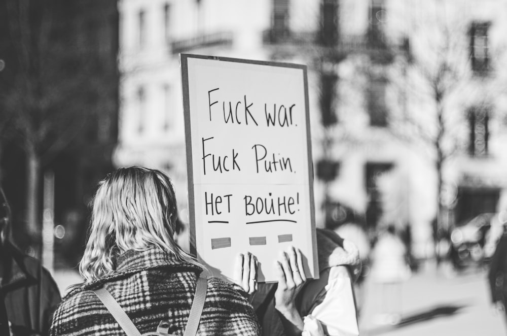 a woman holding a sign on the side of the road