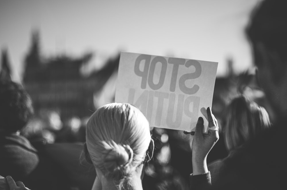 a woman holding a sign that reads stop pluto