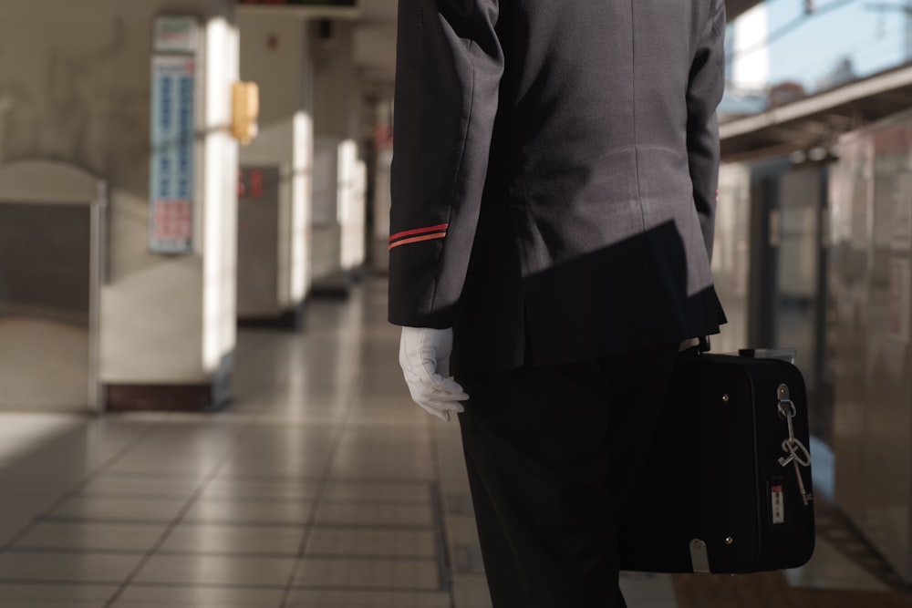 Un uomo in giacca e cravatta e guanti bianchi che tiene una valigetta