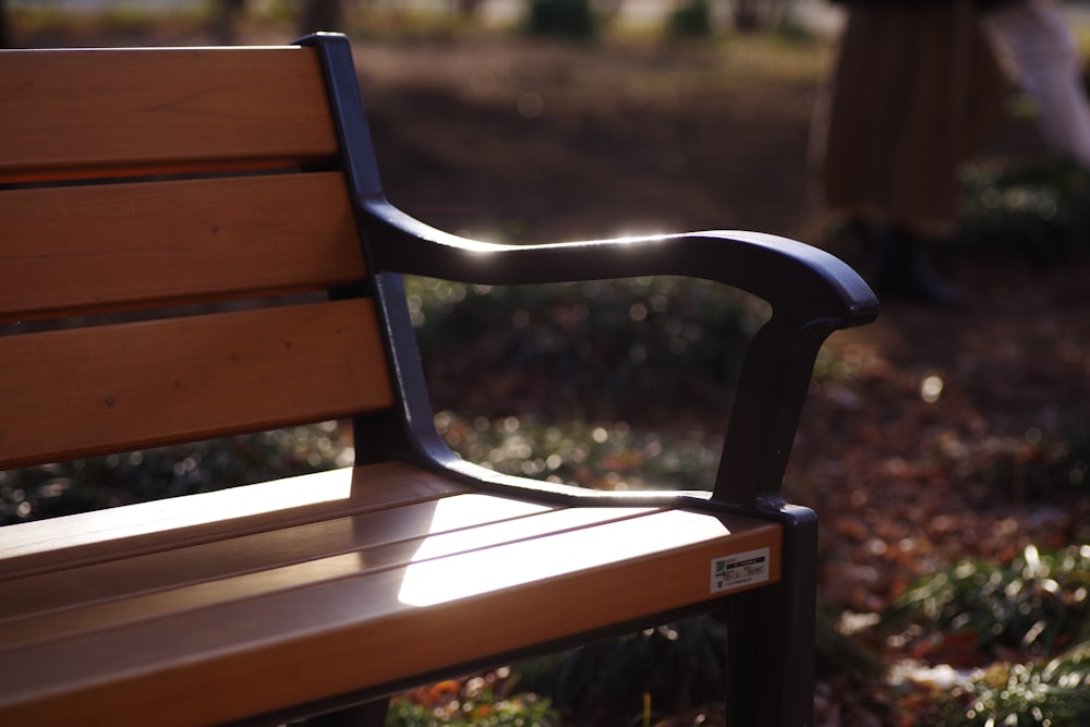 a wooden bench in a park with a person walking by