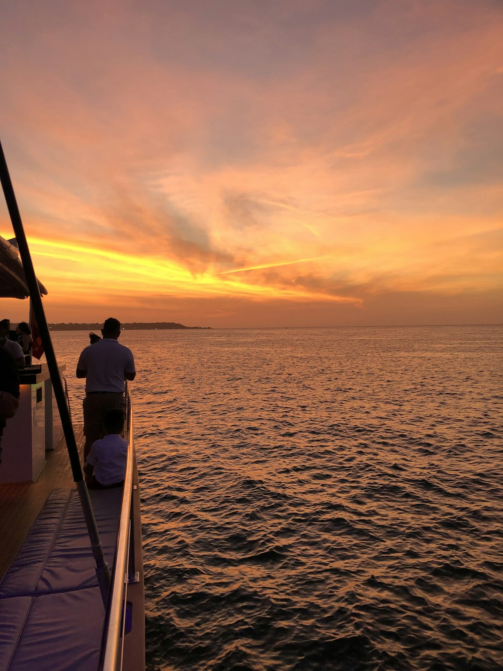 a group of people sitting on a boat watching the sunset