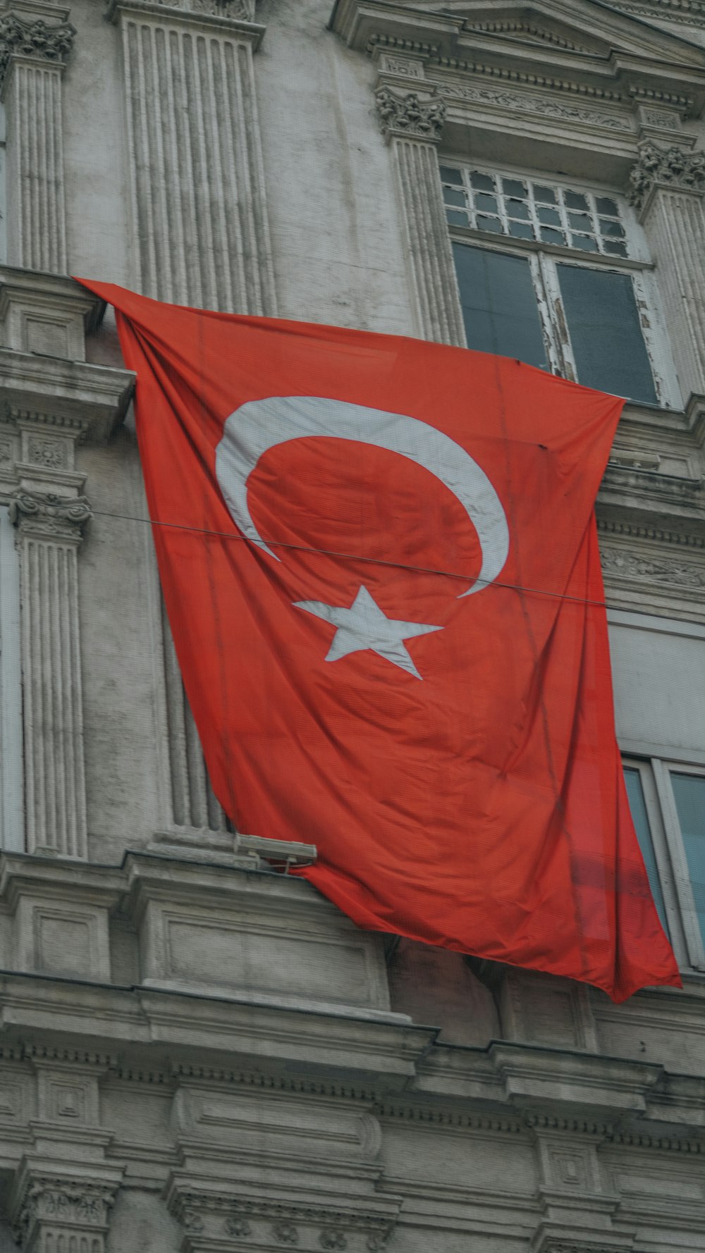 a large red flag hanging from the side of a building