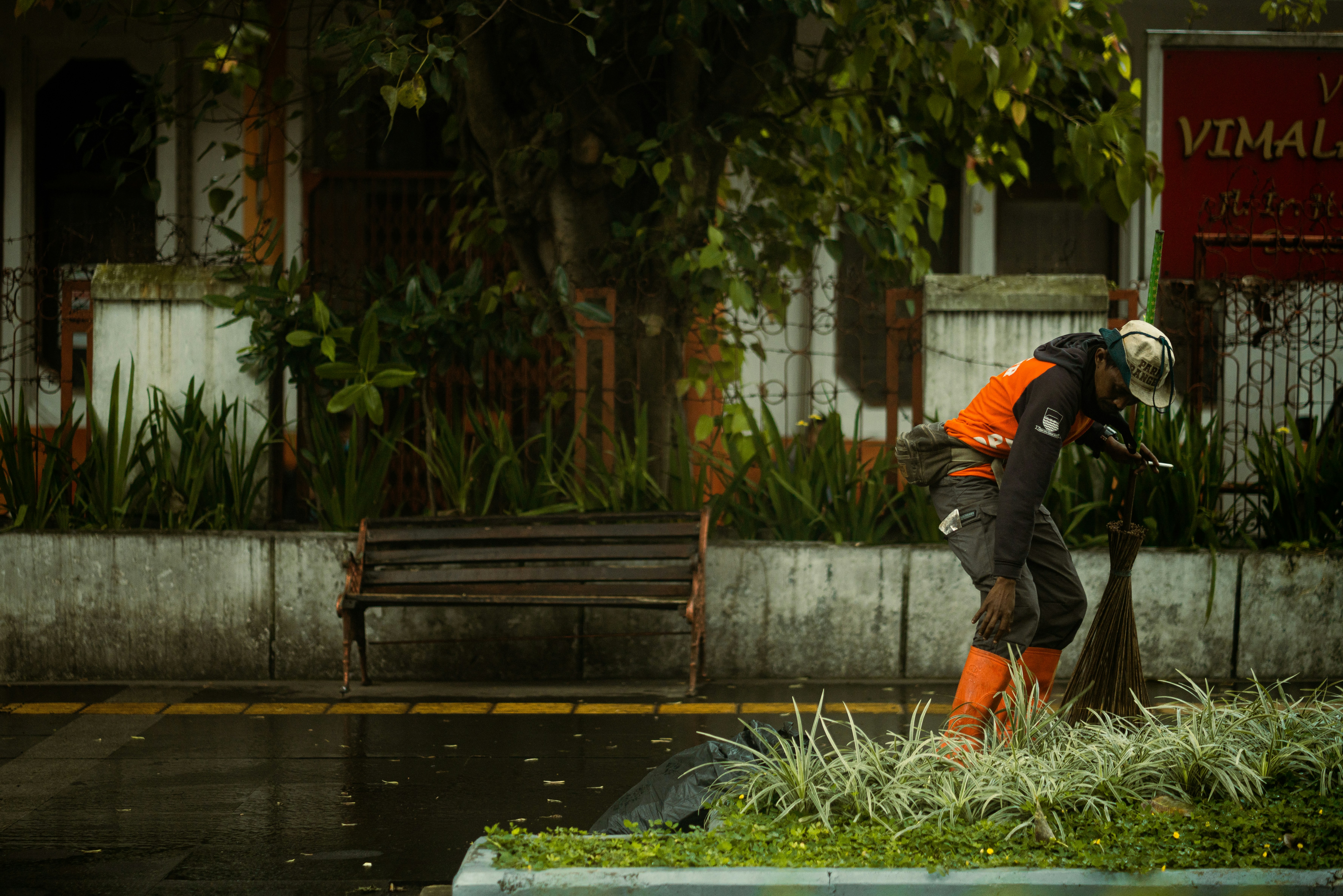 Seorang pria berjaket oranye dan helm putih membersihkan jalan