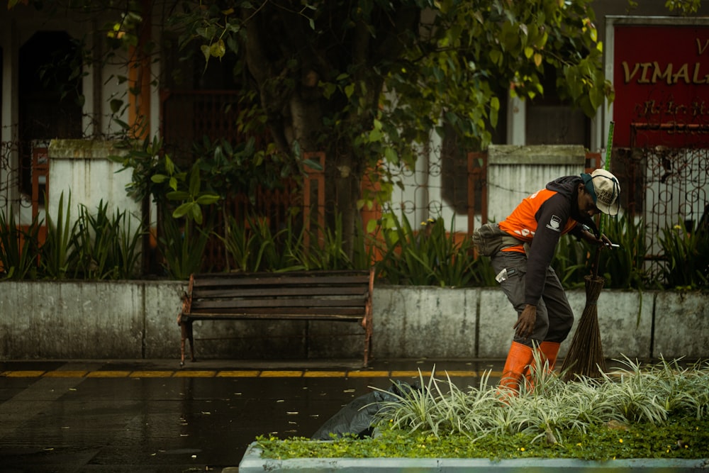 a man in an orange jacket and white helmet cleaning a street