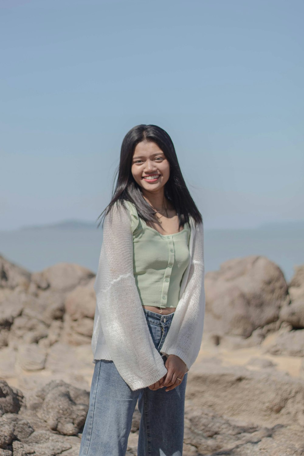 a woman standing on top of a rocky beach