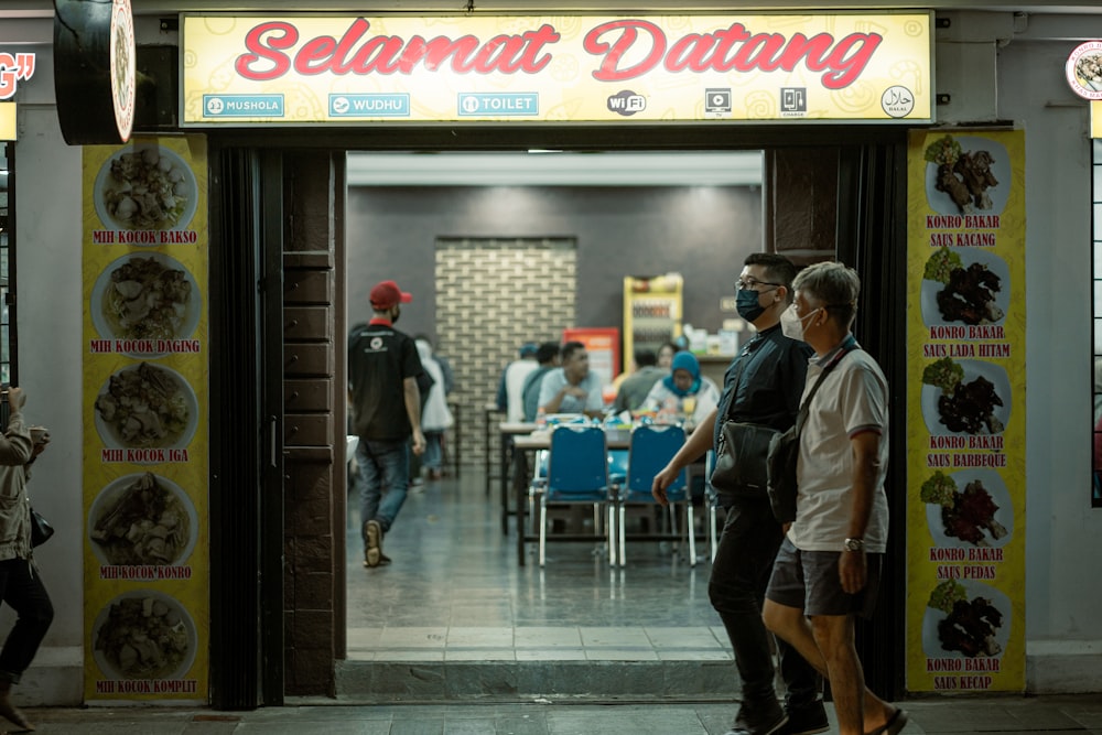 a couple of people that are standing in front of a restaurant