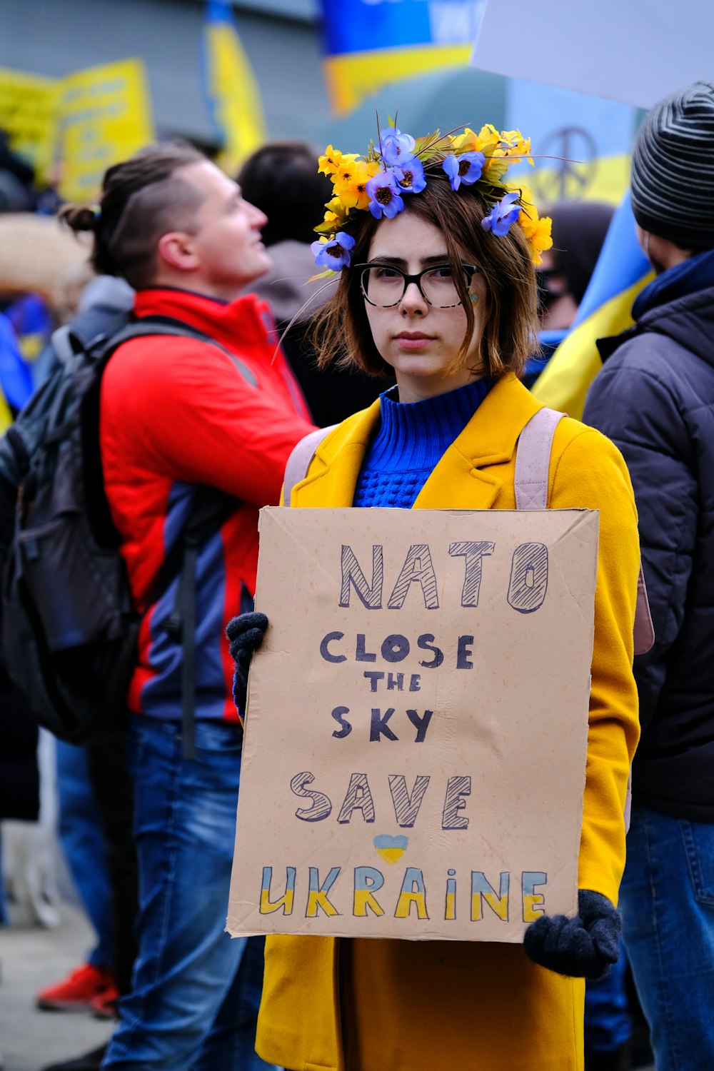 a woman holding a sign that says not to close the sky save ukraine