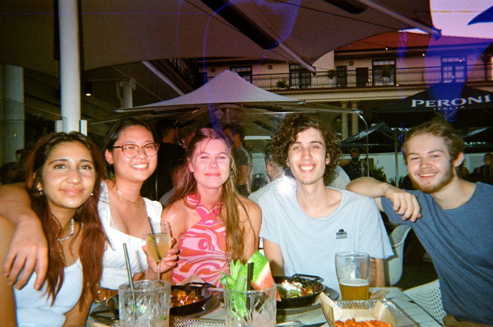 a group of people sitting at a table with food