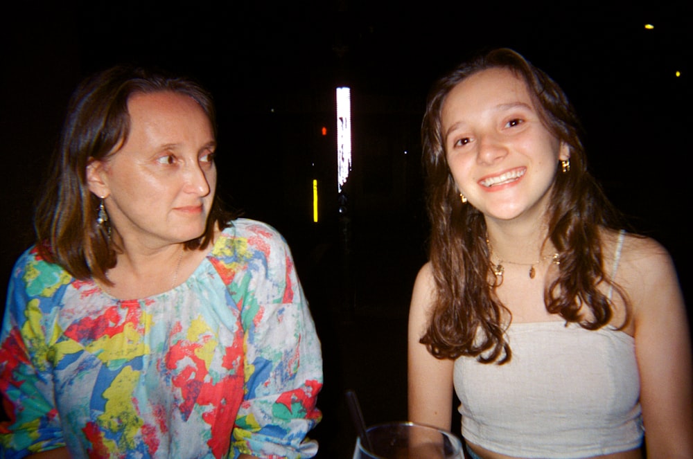 a woman sitting next to another woman at a table