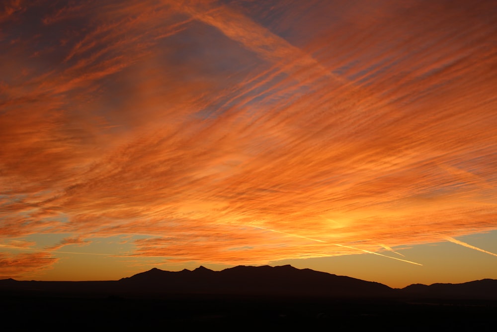 a sunset with clouds and mountains in the background