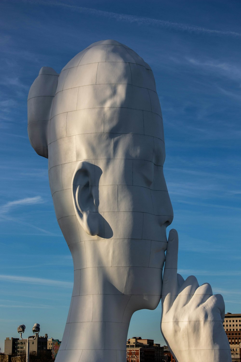 Una gran escultura blanca de una persona sosteniendo un teléfono celular en su oreja