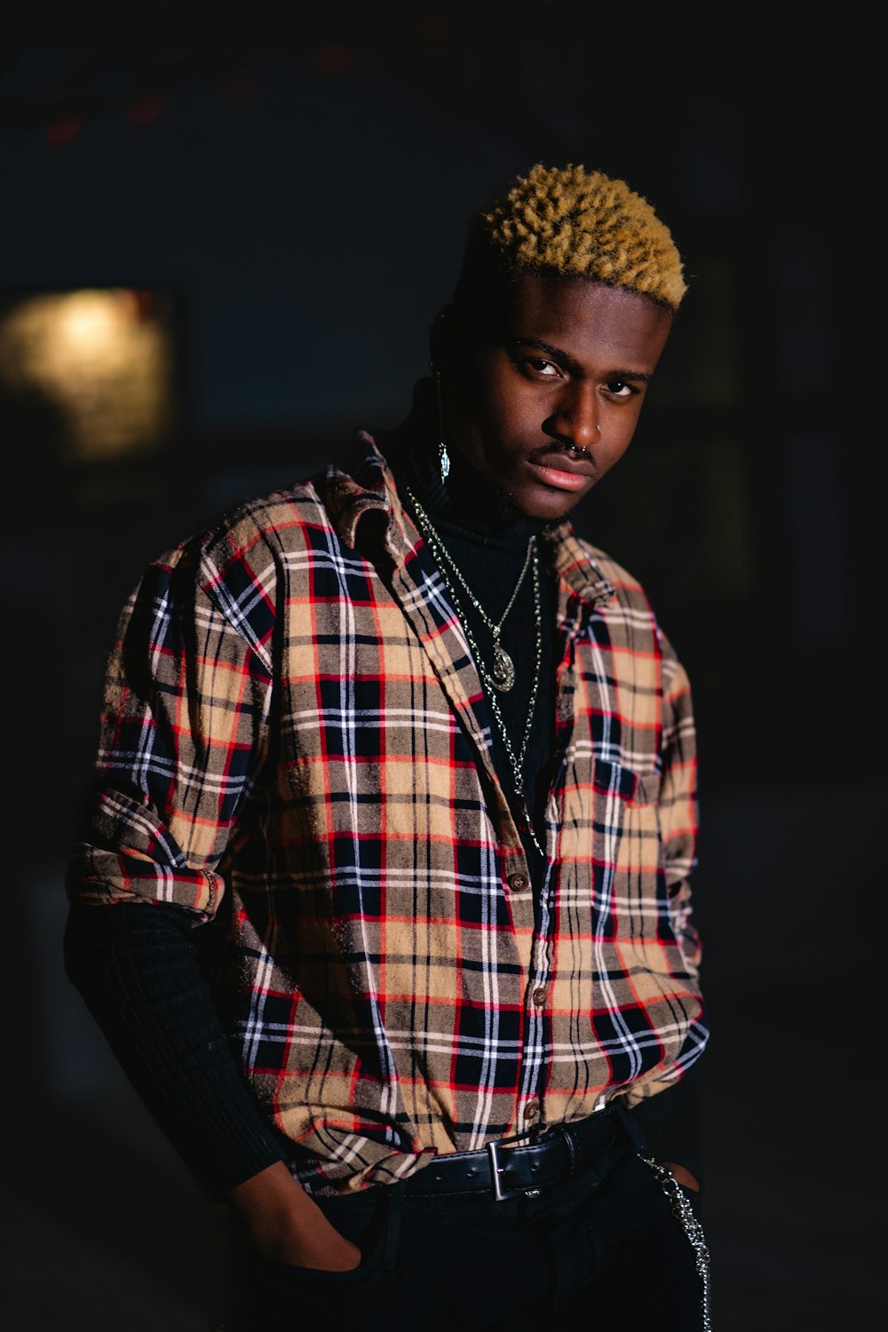 a man in a plaid shirt standing in the dark