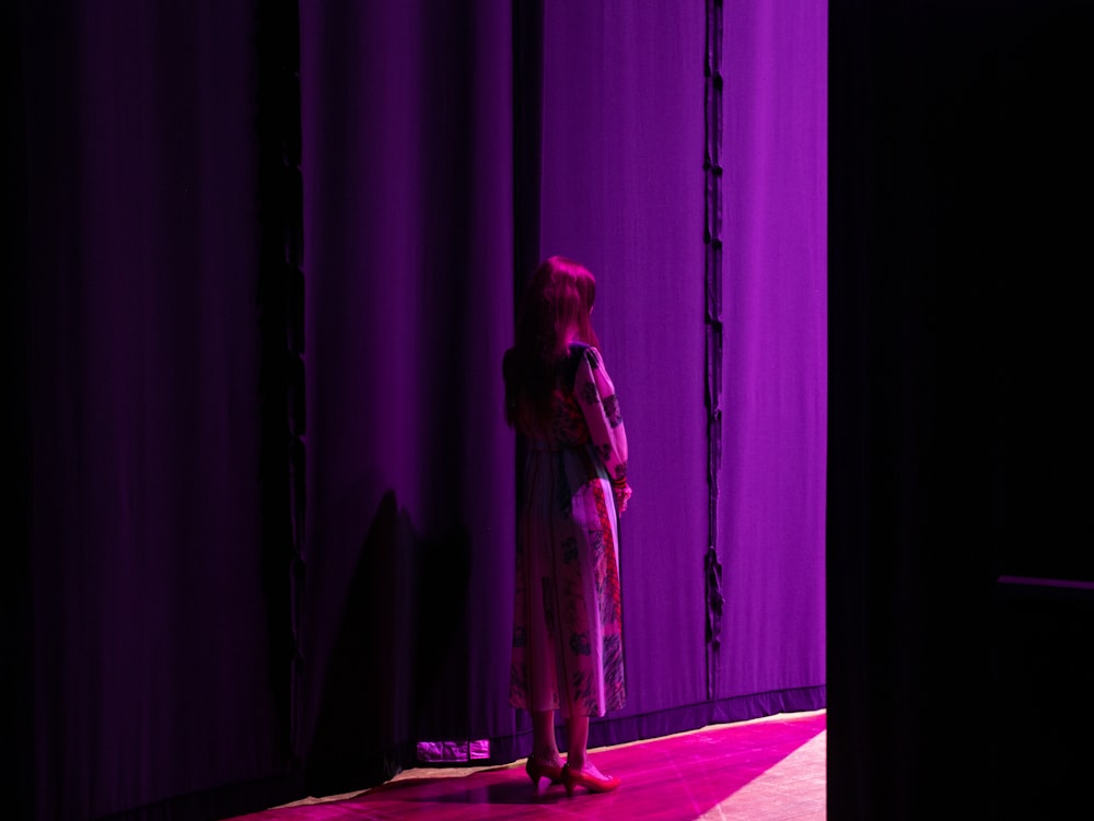 a woman standing in front of a purple curtain
