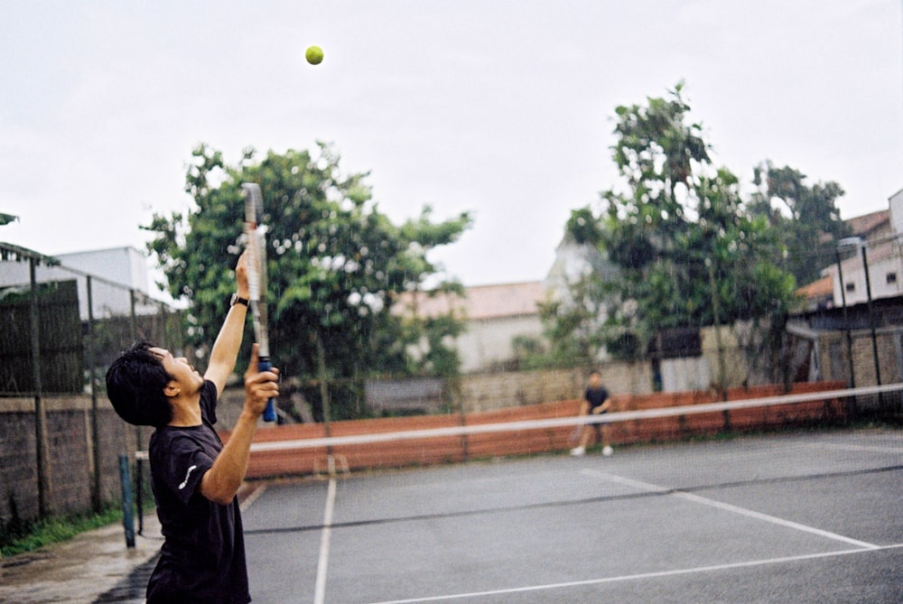 a man holding a tennis racquet on top of a tennis court