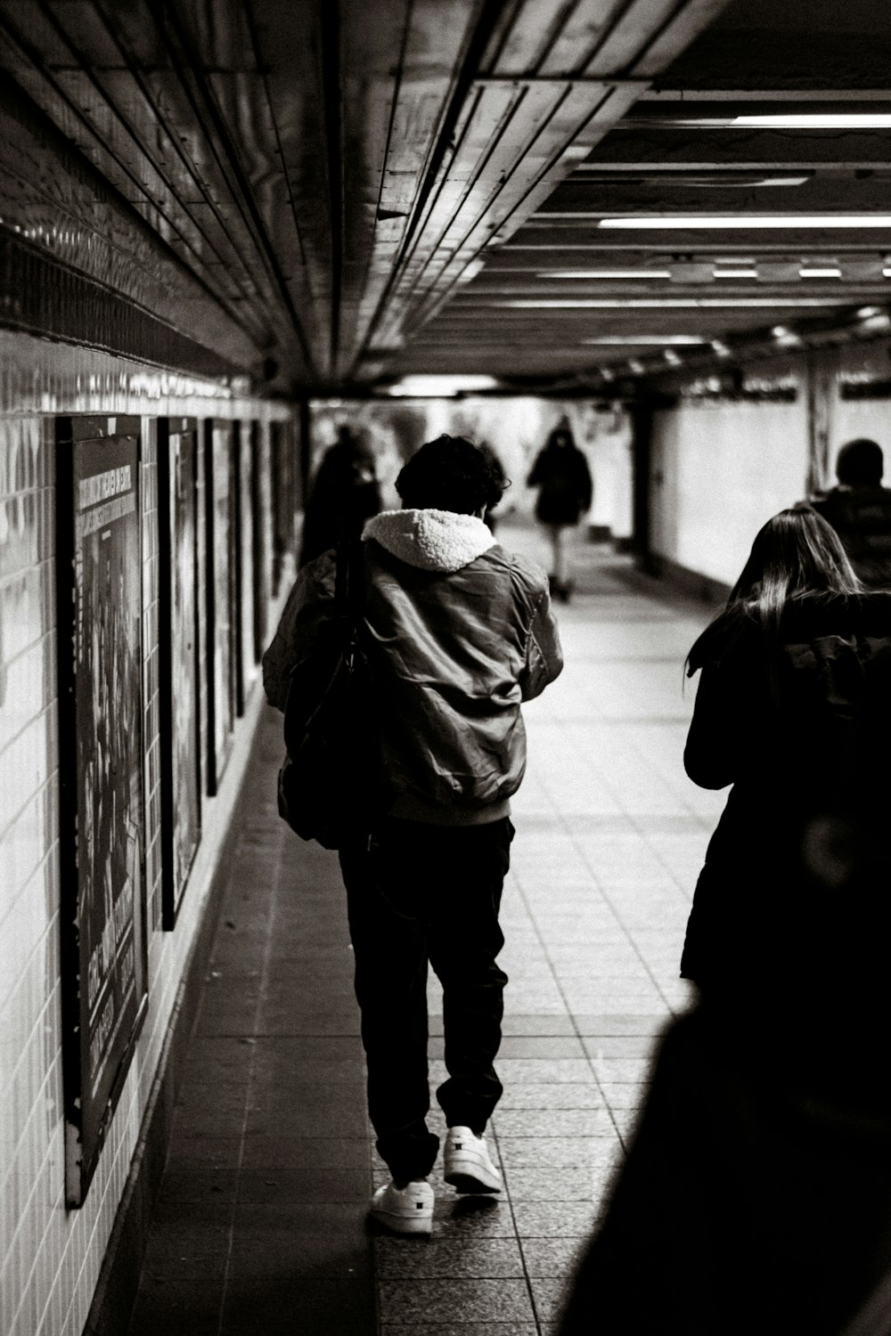 a black and white photo of people walking in a subway