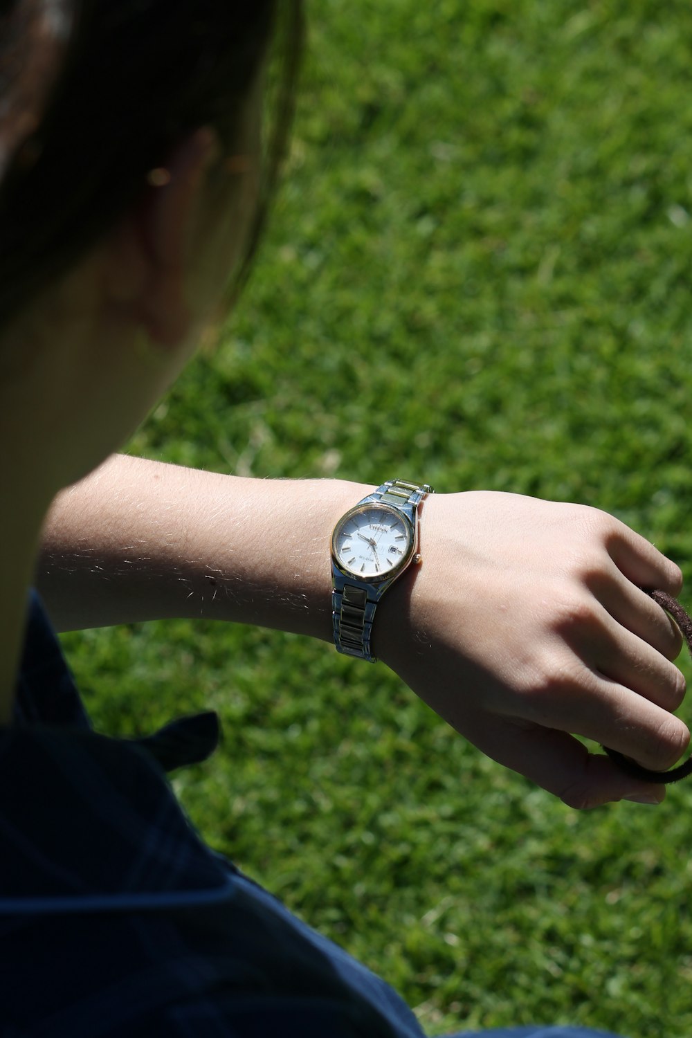a person sitting in the grass with a watch on their wrist
