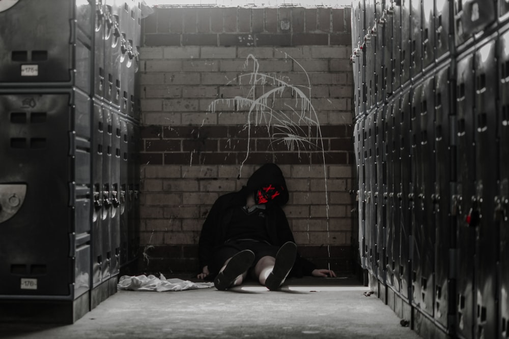 a person sitting on the ground in a room with lockers