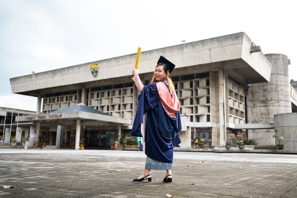 a woman in a graduation gown holding a bat