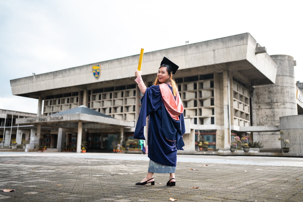 Una donna in un abito di laurea che tiene un pipistrello