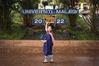 a woman in a graduation gown standing in front of a sign