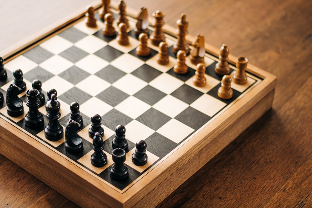 a wooden chess board with black and white chess pieces