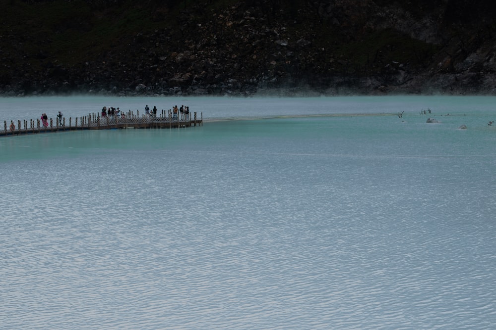 a group of people standing on a bridge over a body of water