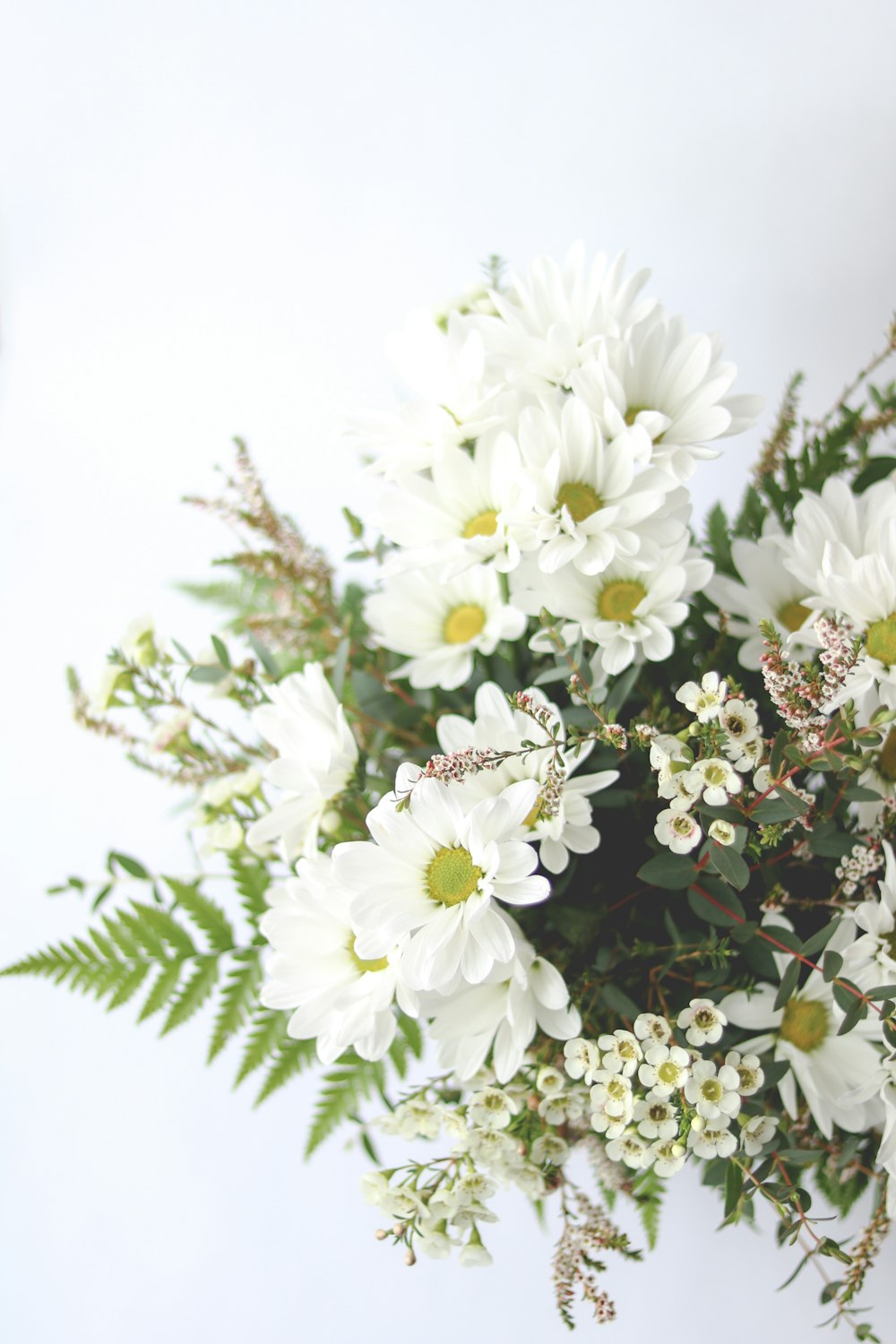 a vase filled with white flowers and greenery