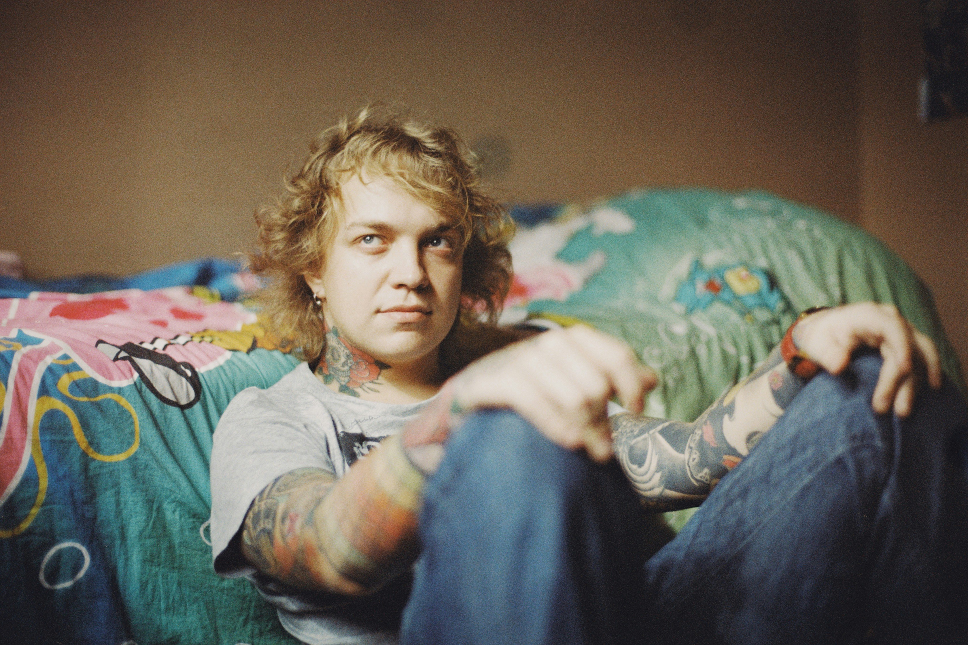 a man with tattoos sitting on a bed