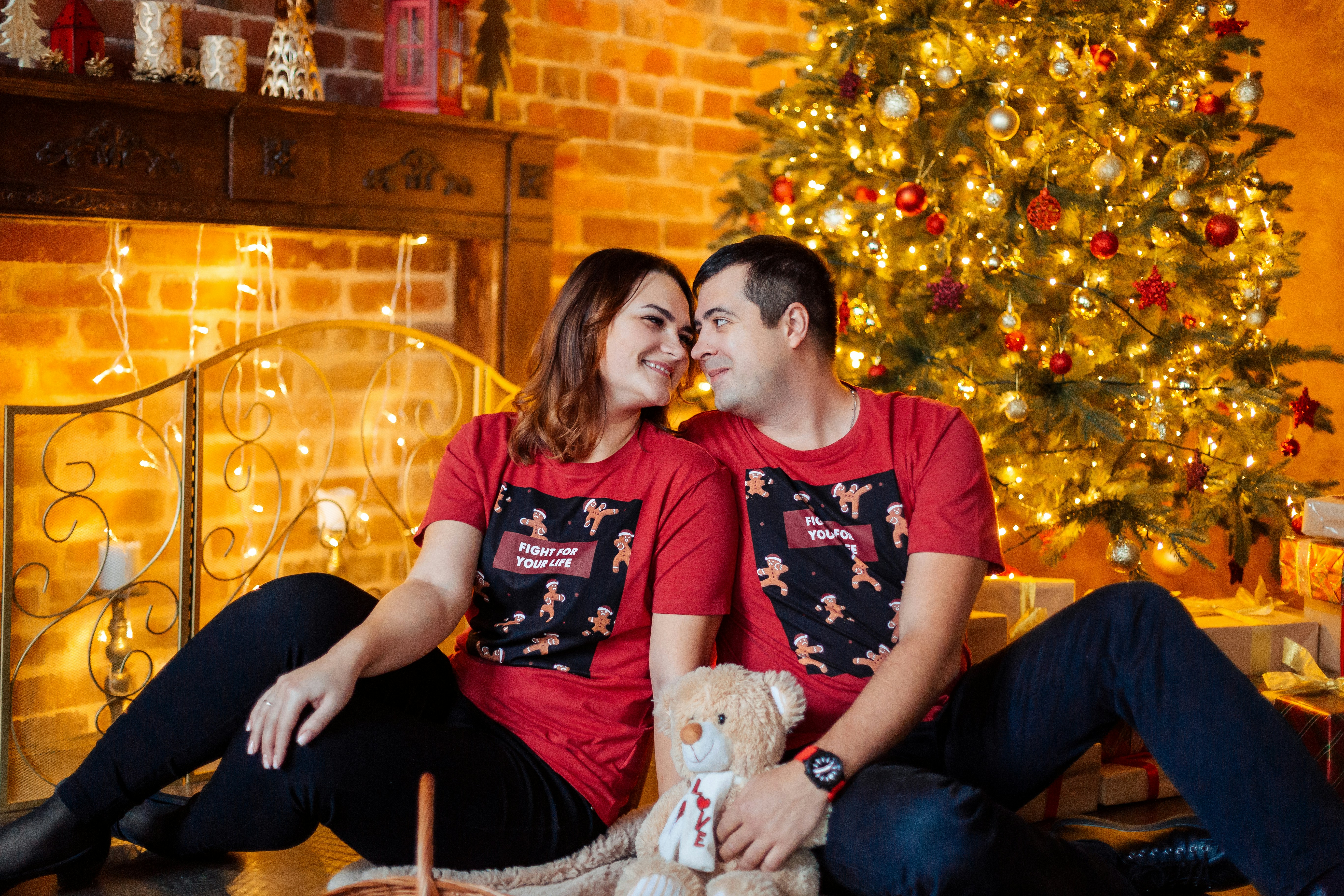 a man and woman sitting next to a christmas tree